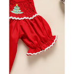 Red baby bloomers with a Christmas tree design on a beige background