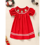 Red dress with white trim and Christmas tree embroidery on a beige background