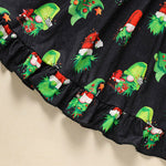 Black fabric with green and red Christmas-themed designs on a beige background